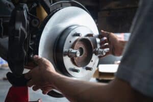 Brake Service Guide for Japanese Cars | Speedy Roo Motorsports | Aurora, CO. image of mechanic changing brakes in shop.